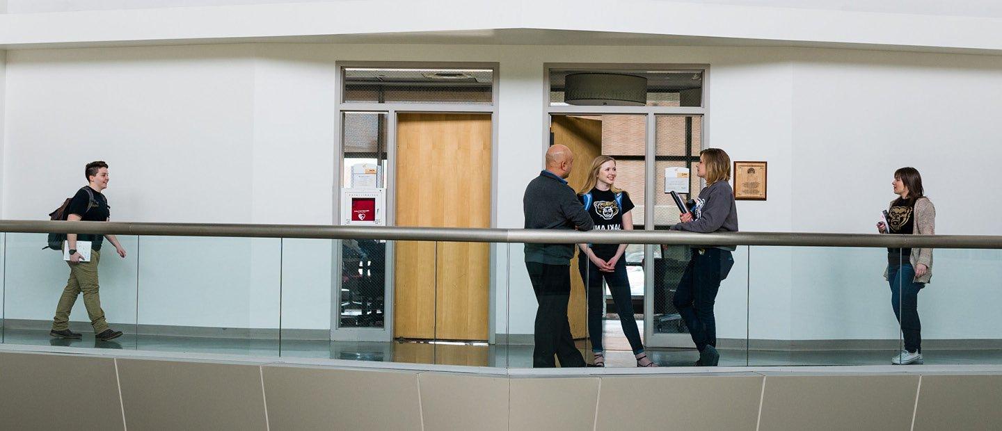 students gathering in a hallway in front of two office doors